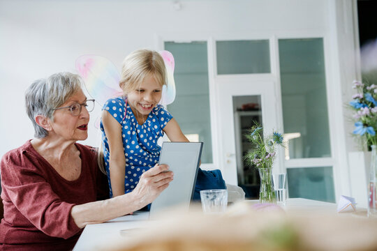 Grandmother and grandchild looking at a tablet at home