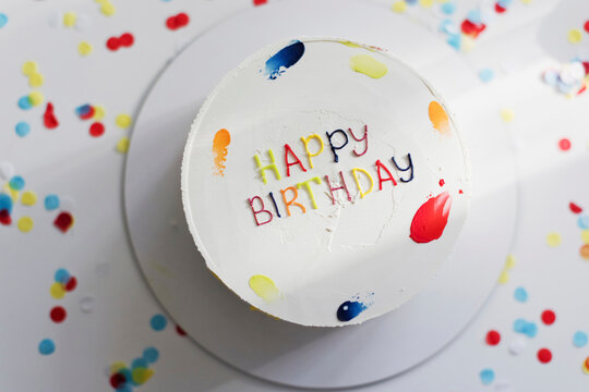Birthday cake amidst multi colored confetti on table