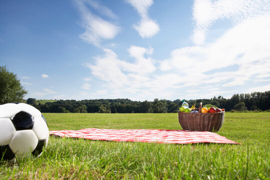 Germany, Cologne, Picnic basket and soccer ball in meadow