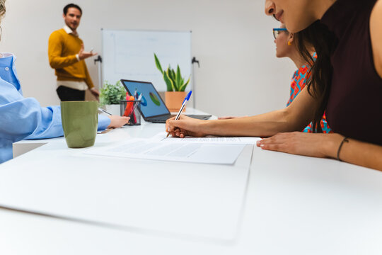 Businesswoman writing notes during an office meeting presentation