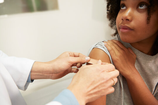 Doctor applying adhesive bandage on patient's arm in medical room