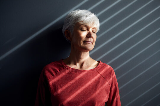 Portrait of senior woman with eyes closed leaning against wall