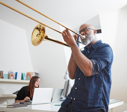 Man playing trombone at home office