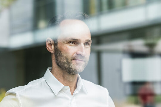Portrait of smiling businessman looking out of window