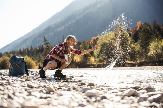 Austria, Alps, woman on a hiking trip splashing with water at a brook