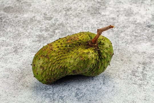 Whole raw soursop fruit on textured gray background