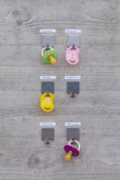 Pacifiers hanging on concrete wall with name tags