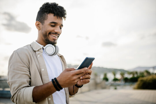 Happy man with wireless headphones using smart phone