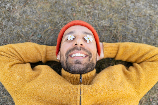 Smiling outdoors with white flowers covering eyes in spring