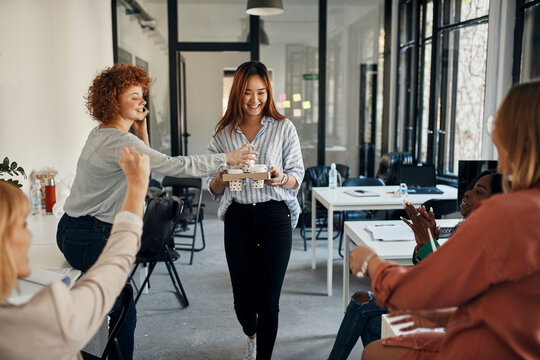 Businesswoman serving coffee to colleagues in office