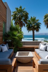 Fototapeta premium Minimal seaside deck with wooden sofas and central stone fire pit overlooking palm trees and ocean for patio background and outdoor seating design
