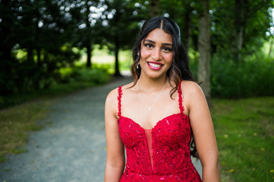 Smiling young woman in red dress on park path