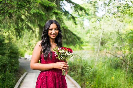 Smiling teenage girl in red dress holding bouquet