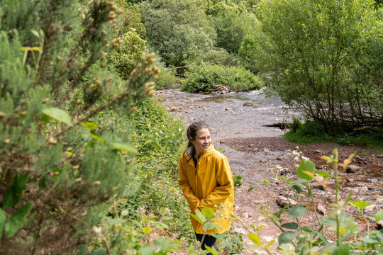Woman wearing yellow raincoat exploring nature by river