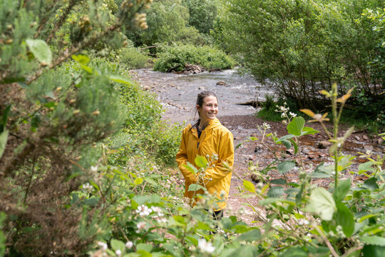 Woman hiking outdoors smiling by a flowing river