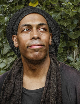 Thoughtful man with dreadlocks looking up outdoors