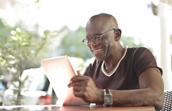 Happy senior man using digital tablet at an outdoor cafe