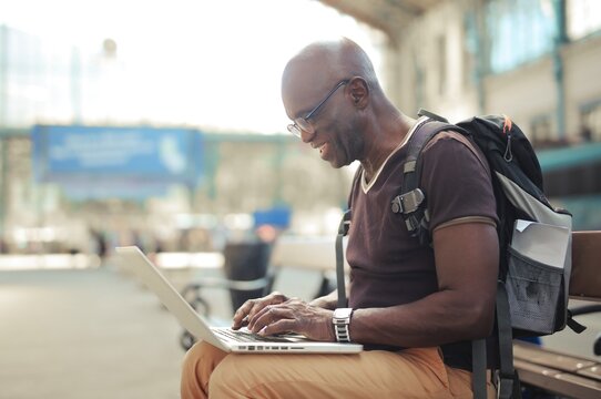 Smiling senior man using laptop at train station