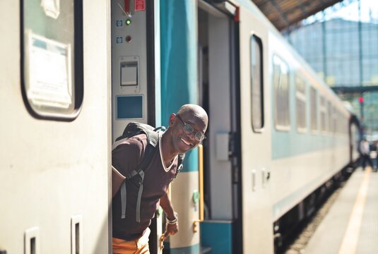 Smiling man with backpack getting off a train