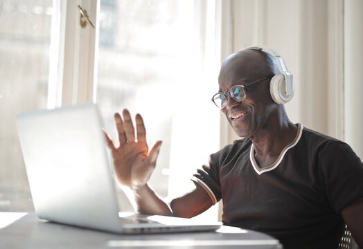 Happy senior Black man waves during video call