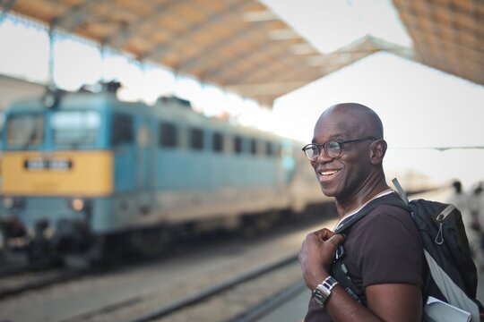 Happy mature man with backpack at a train station