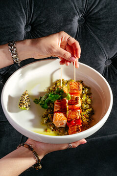 Woman serving a beautiful dish of salmon skewers