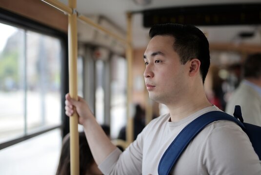 Young Asian man looking out a bus window