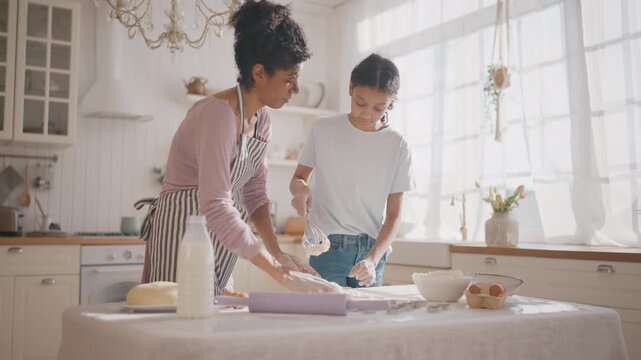 African american woman and daughter making dough from organic gluten-free flour. Culinary master class for adolescent and teenager, mother teaching teen girl to cook. Family dinner, homemade bakery
