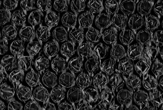 Black bubble wrap texture close up. Abstract protective packaging background ideal for shipping, logistics, design and industrial concepts.