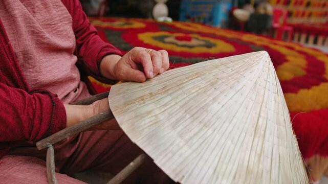 Close up of hands making traditional conical hat in a village market, showcasing authentic craftsmanship, Vietnam