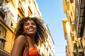 Obraz premium Happy young woman smiling looking up in urban street