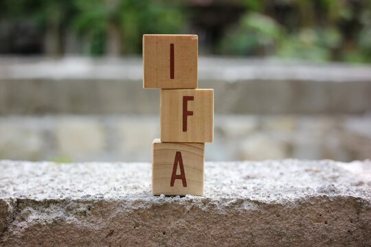 Wooden letter blocks spelling IFA with a blurred background. Can be used for business and financial concepts. Selective focus.