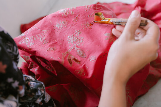 Javanese, southeast Asia women hand drawing batik on red cloth using canting. Traditional concept, Indonesia culture