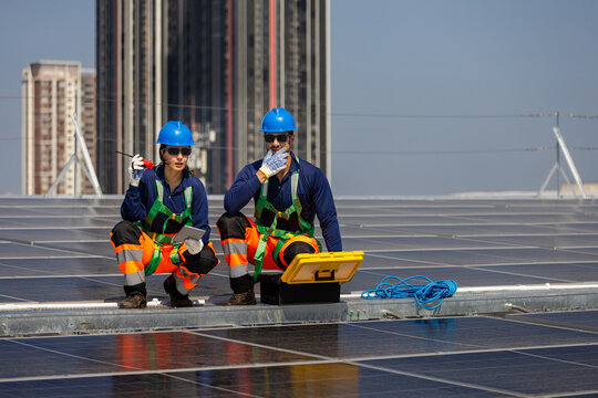 Workers installing solar panels on rooftop, Solar energy technicians team inspecting photovoltaic modules on industrial roof, Professional team maintaining solar panel system for sustainable