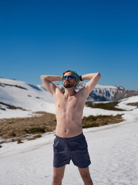 Shirtless man practicing hardening on snowy slope in Carpathians