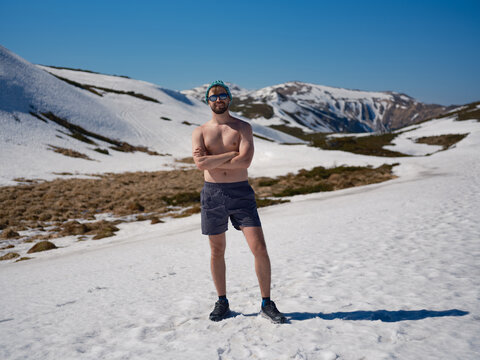 Smiling shirtless man practicing hardening on snowy slope in Carpathians