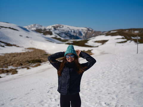 Smiling woman wearing beanie on snowy mountain slope in Carpathians