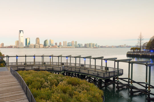 Jersey City skyline overlooking the Hudson River from a wooden pier, capturing an urban waterfront destination for travel, tourism, and city exploration, Jersey City, New Jersey, USA.
