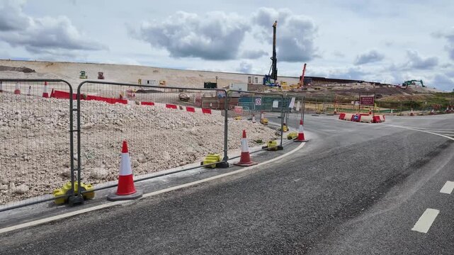 Winchester Hampshire England UK. 03.06.2026. Video. Excavators and other heavy equipment are actively engaged in earthmoving operations on a vast construction site with a backdrop of dramatic clouds