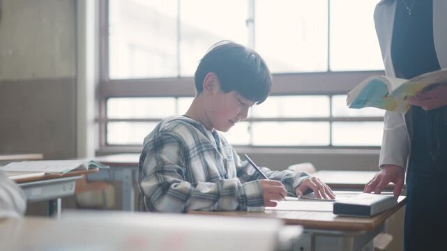 先生に勉強を教えてもらう小学生