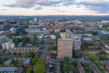 Obraz premium Aerial image of Manchester showing university campus architecture, modern apartment blocks, and residential streets at sunset.