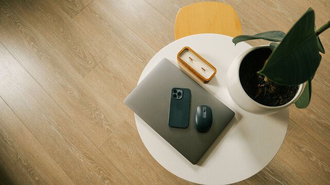Modern home office setup with laptop, phone, mouse, and plant on a round table