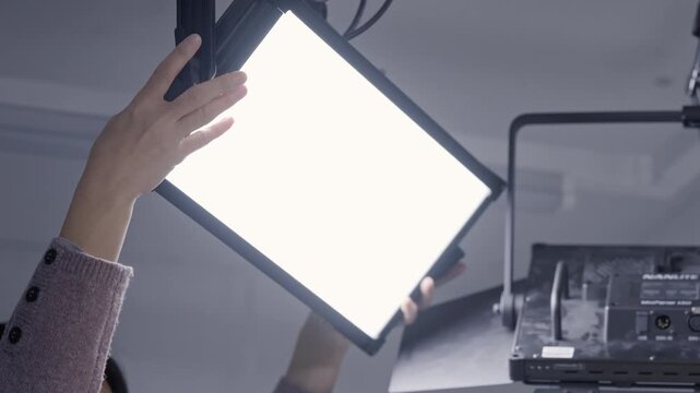Close up of Lighting Technician Hand Adjusting Professional LED Panel Light with Nanlite Gear in Studio