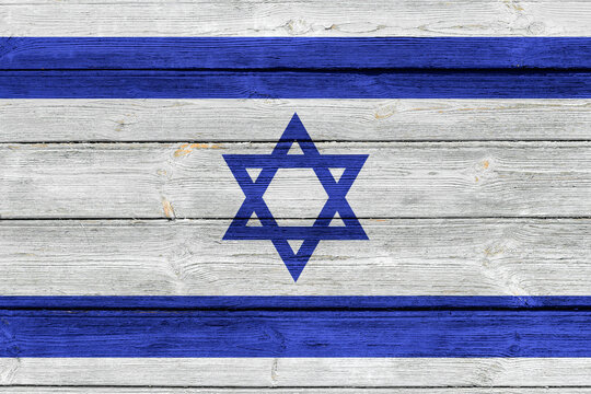 Flag of Israel on an old wooden surface with cracked paint.