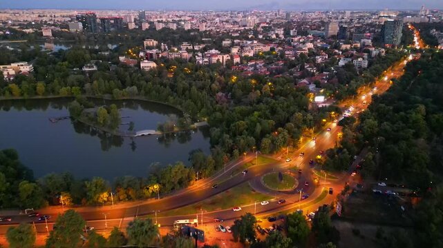 Nighttime aerial drone perspective of Bucharest cityscape, showing Herastrau park surroundings and the glowing modern office buildings in Pipera financial center, Romania.