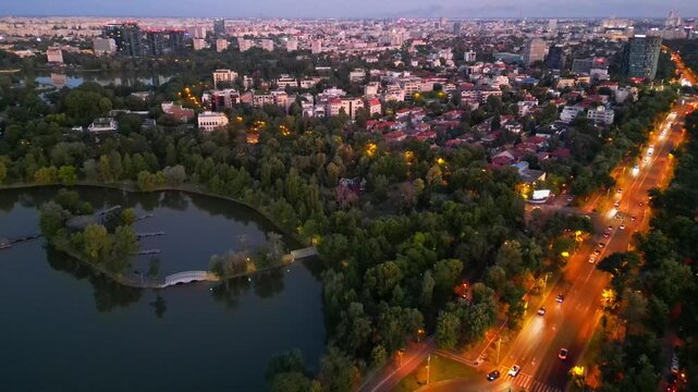 Nighttime aerial drone perspective of Bucharest cityscape, showing Herastrau park surroundings and the glowing modern office buildings in Pipera financial center, Romania.