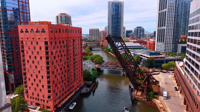 Boat passes under the lifted metal bridge by the narrow river. Drone footage descends in the neighborhood of Chicago, Illinois, USA.