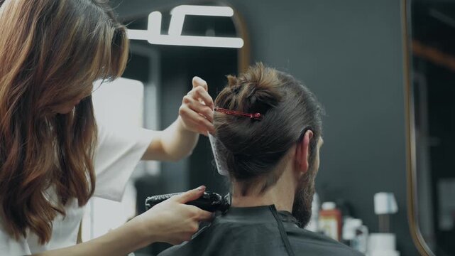 Close up of barber trimming neck hair with electric clipper during beard grooming procedure in modern barbershop