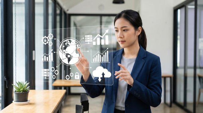 Asian businesswoman interacting with virtual screen displaying global economy, cloud computing and growth charts in modern office representing big data analysis technology.