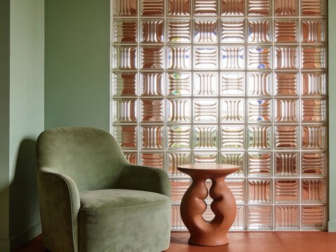 Contemporary lounge corner with green armchair, glass block wall and sculptural side table